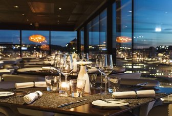 Foto. Restaurang med bord och utsikt över staden.